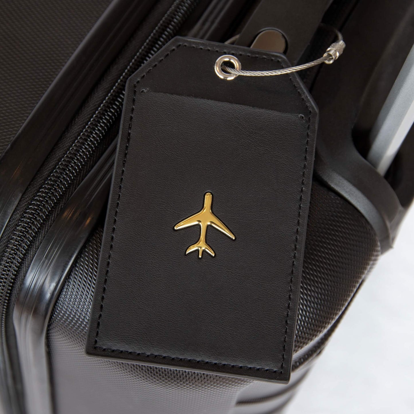 Bagasjelapp i sort lær med et gull fly på. Et produkt i reisegaveesken til henne.