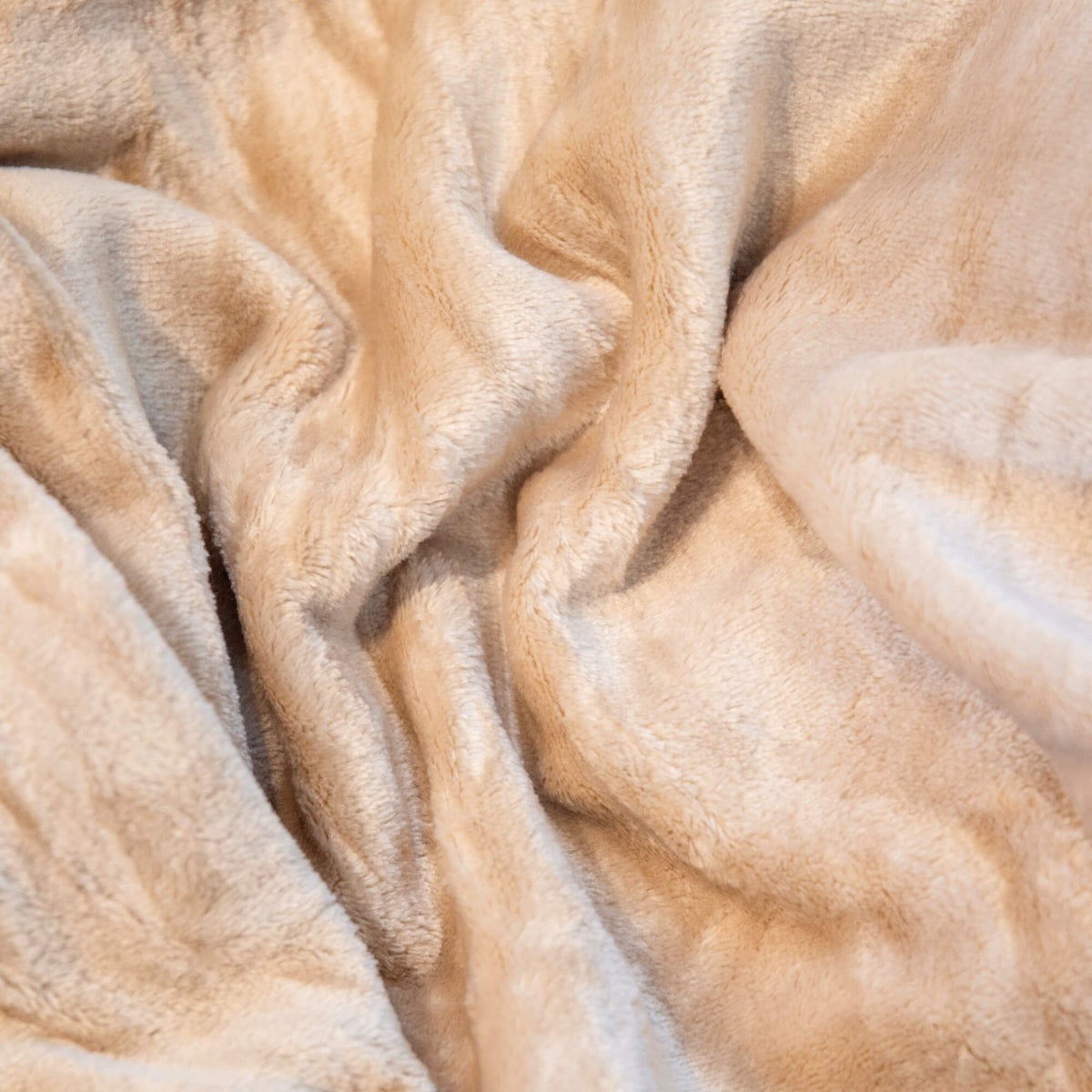 Nærbilde av mykt beige fleecepledd med lun og fluffy overflate