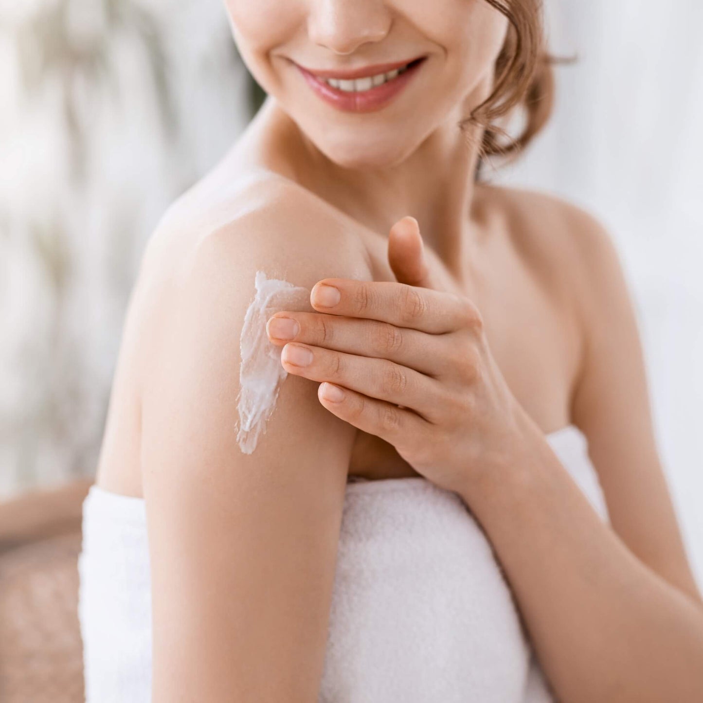 Dame som bruker krem fra badesettet til å smøre seg inn.