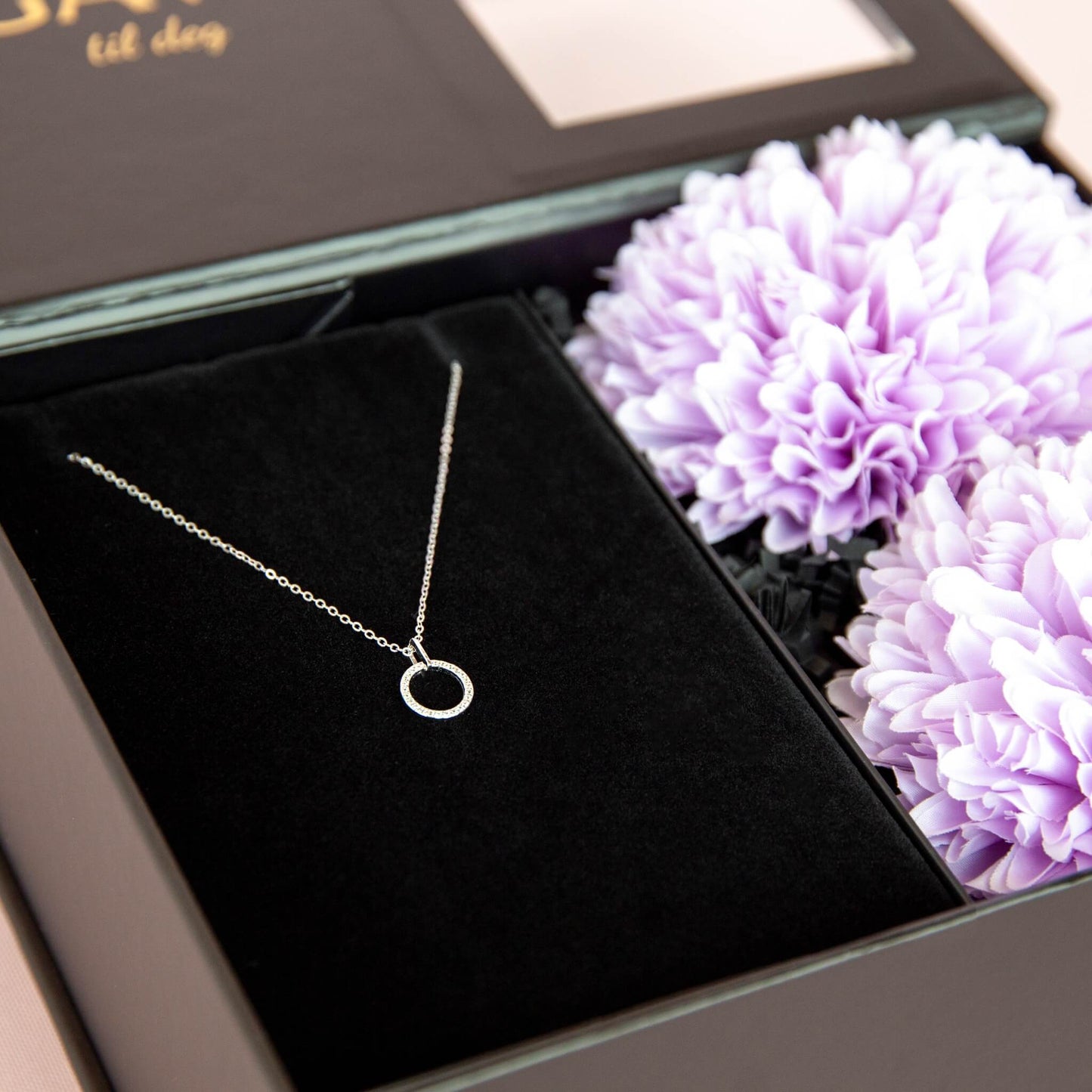 Gave til henne som inneholder et pent smykke i en eksklusiv gaveeske.