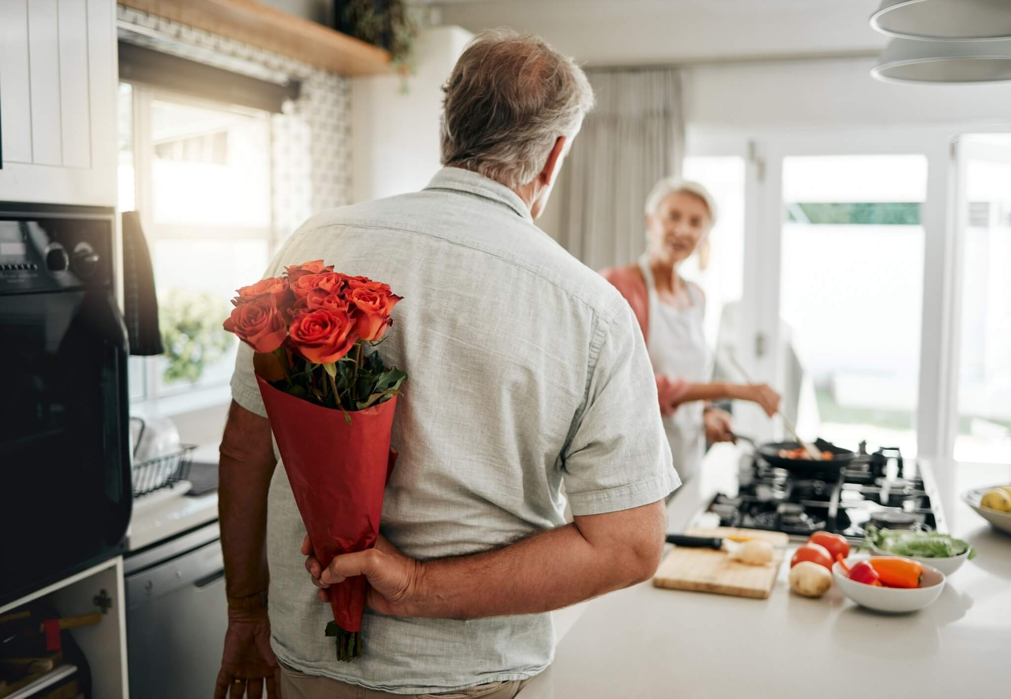 Overraskelse til kjæresten – mann med blomsterbukett bak ryggen klar til å gi en romantisk gave