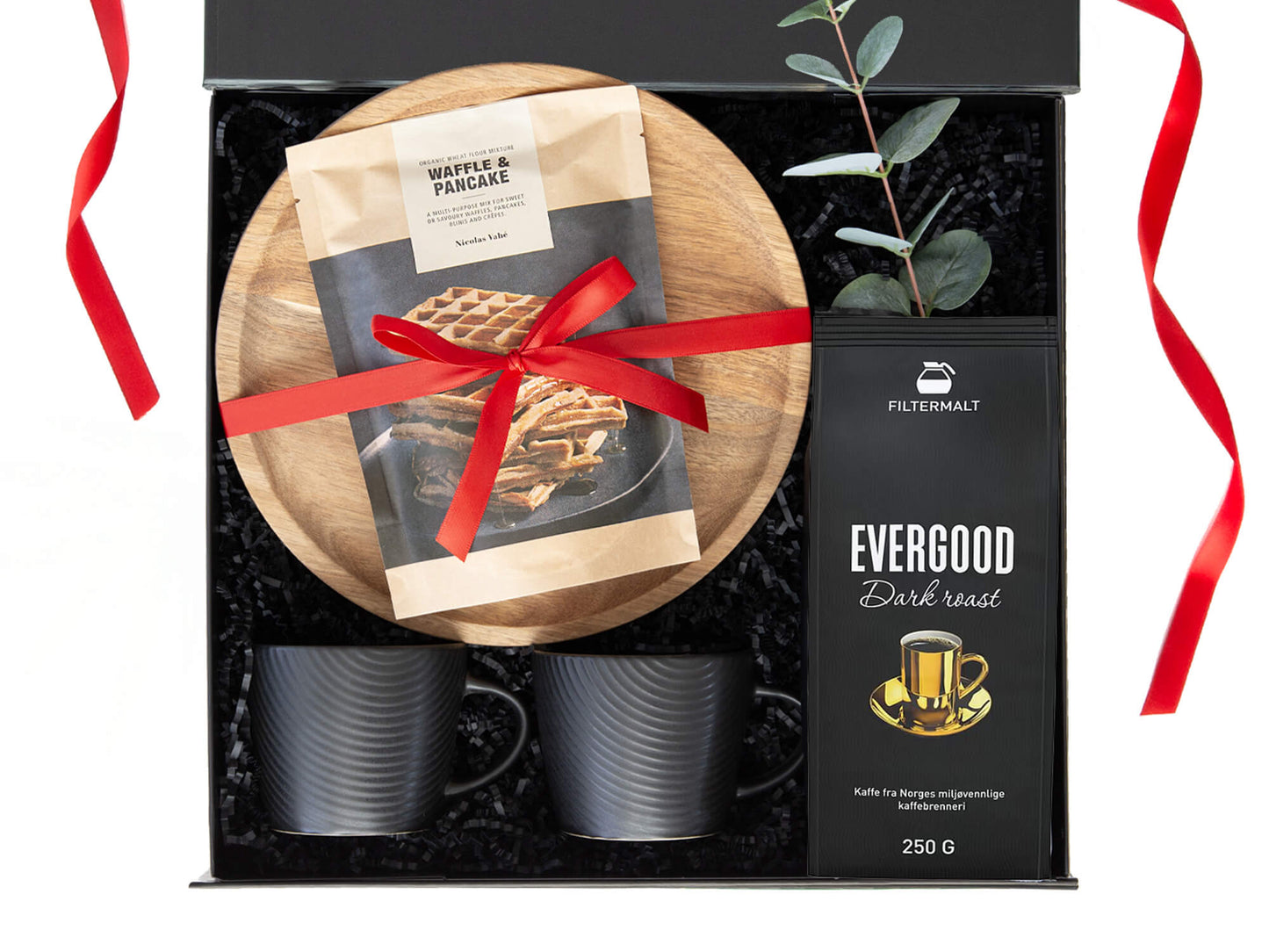 Svart gaveeske med kaffe, kopper, serveringsfat og vaffelmix. Dekorert med juledekor.