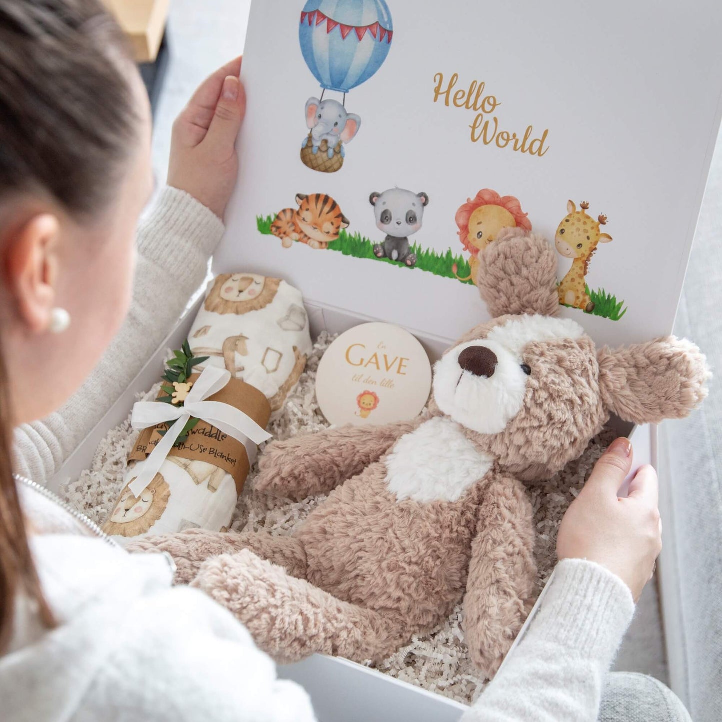 Dame som åpner en babygave med babypledd og en kosebamse.