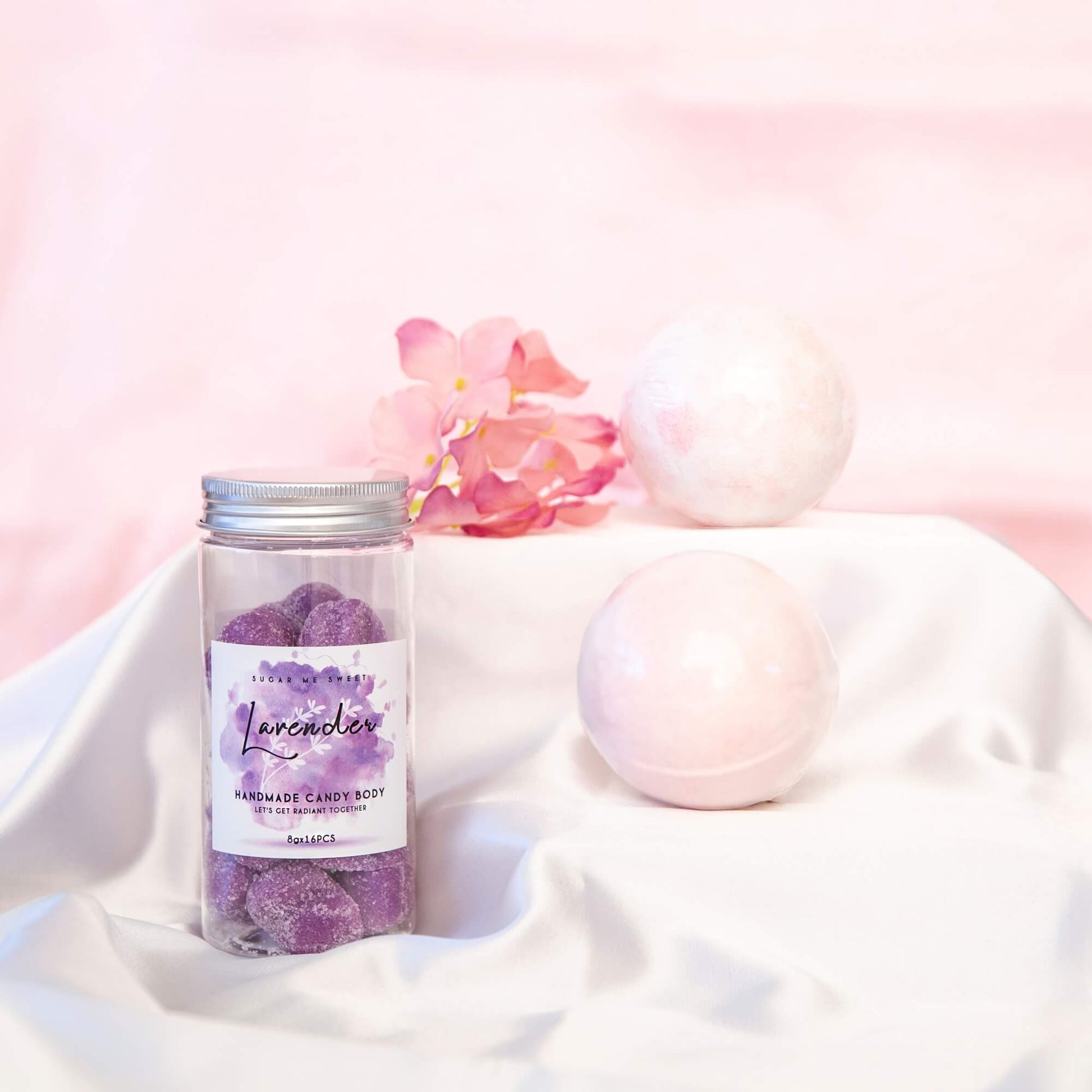 Lekkert display av lavendel bodyscrub og to badebomber på et silkeslør.