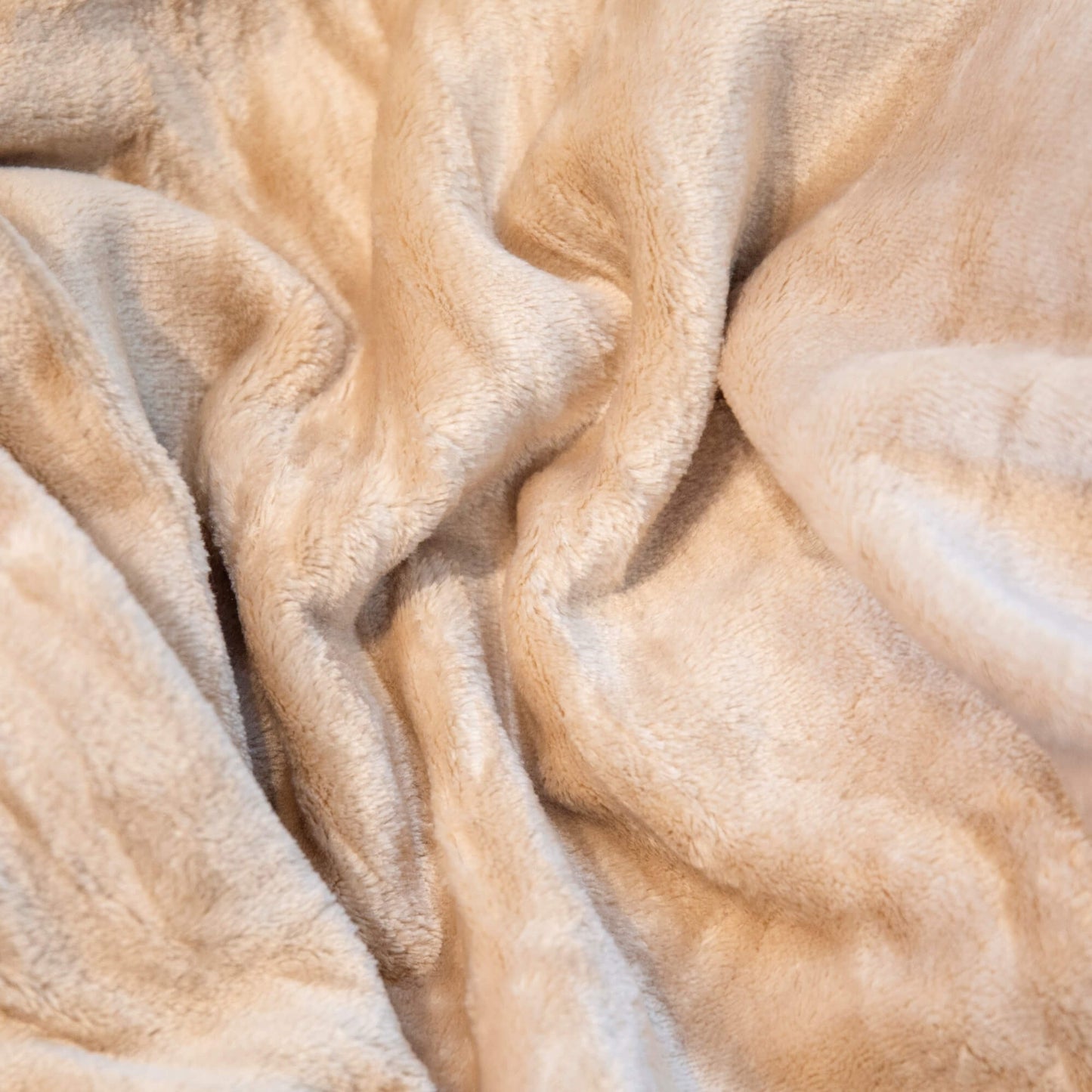 Nærbilde av mykt beige fleecepledd med lun og fluffy overflate