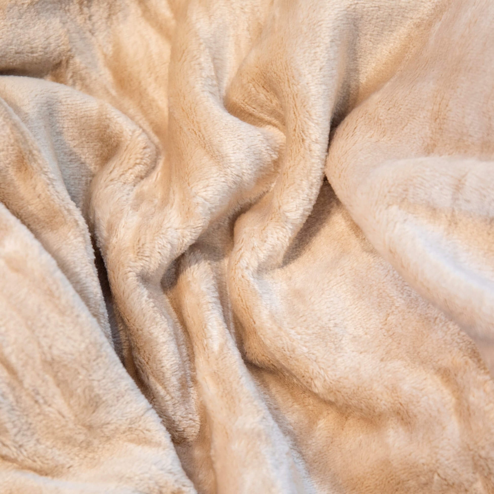 Nærbilde av mykt beige fleecepledd med lun og fluffy overflate