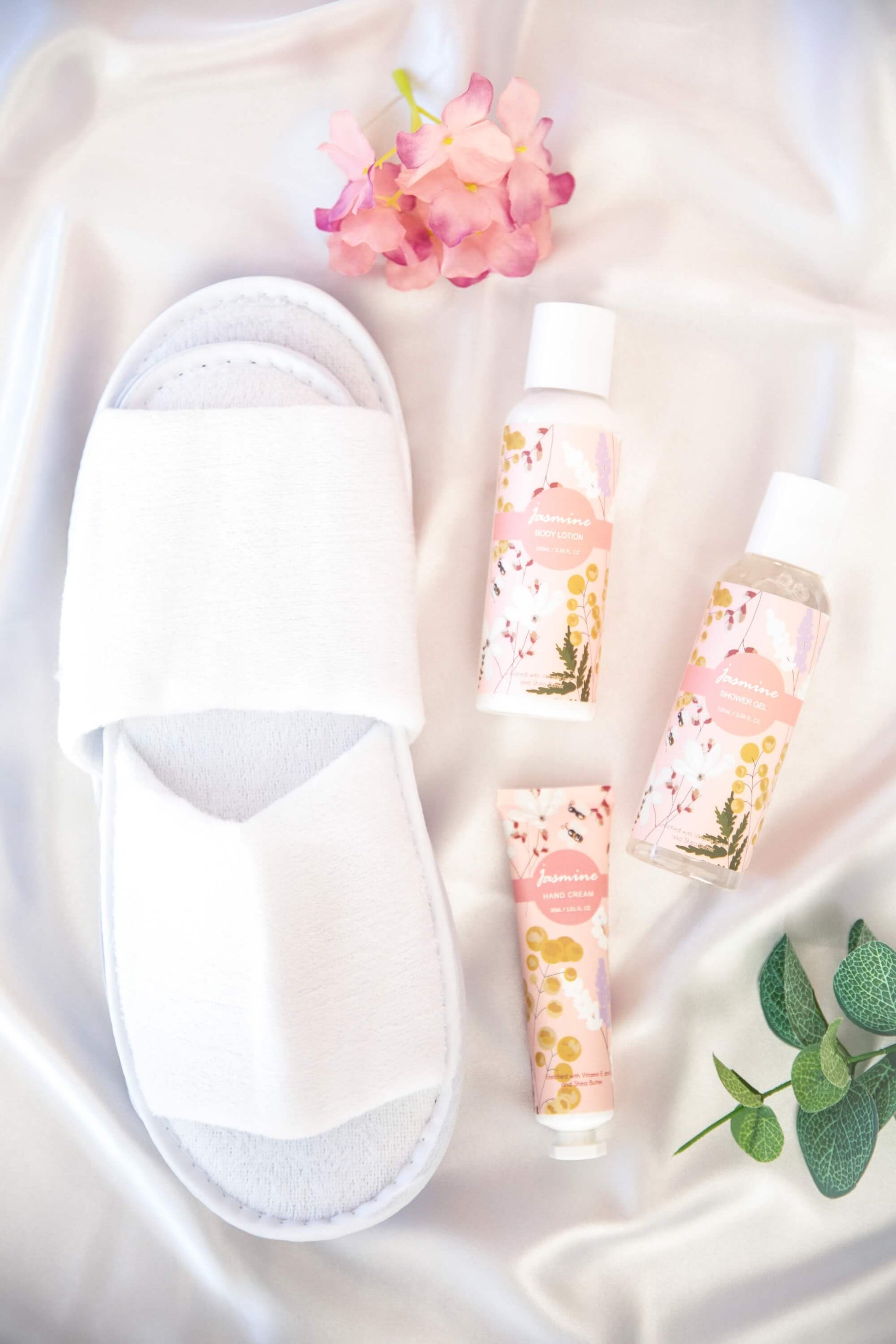Plush slippers og jasmin bodylotion, showergel og håndkrem på en silkebakgrunn.