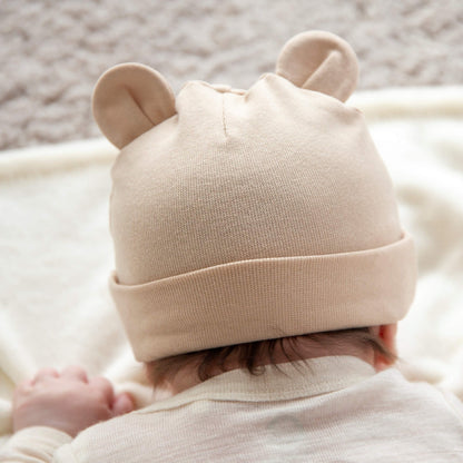 Beige babylue med ører på toppen som blir brukt av en baby.