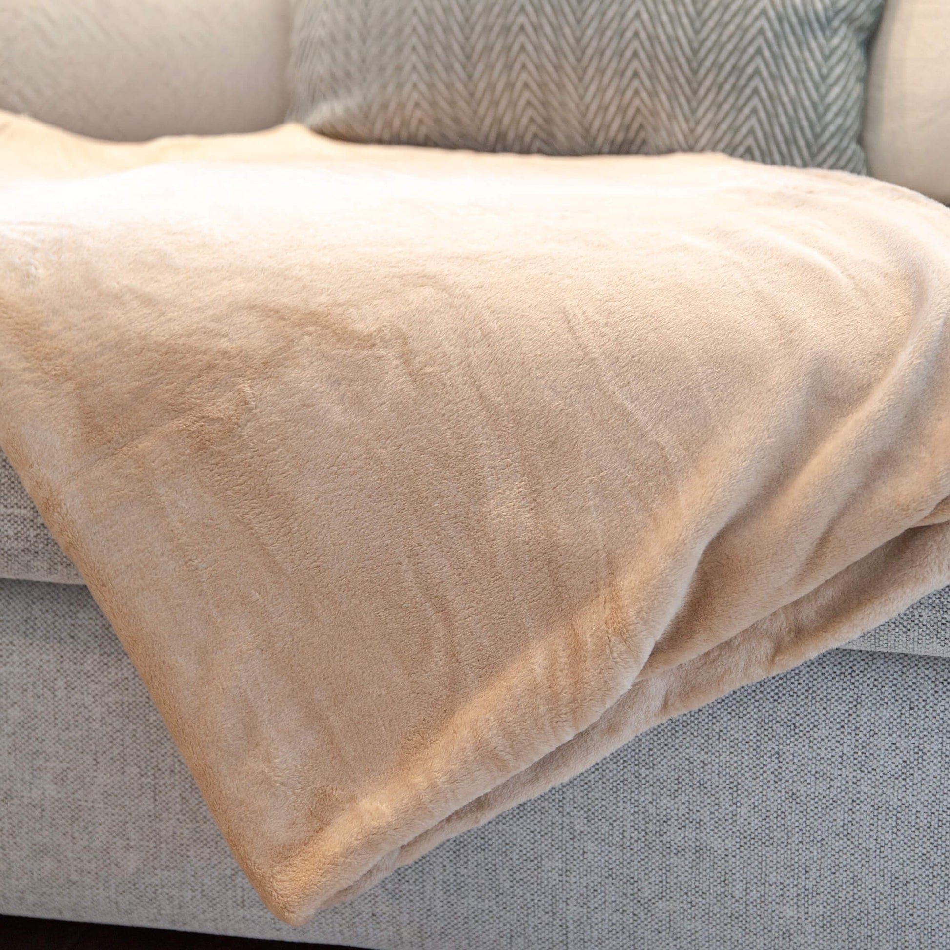 Beige fleecepledd brettet over en grå sofa