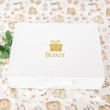Lukket gaveeske med gullfarget Boxit-logo og hvit silkebånd – elegant gaveinnpakning for gaver til babyshower, nyfødt eller nybakte foreldre.
