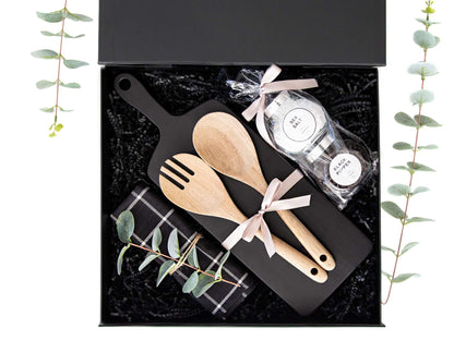 Tresleiver, krydder, kjøkkenhåndkle og sort skjærebrett lekkert dandert i en sort gaveeske.