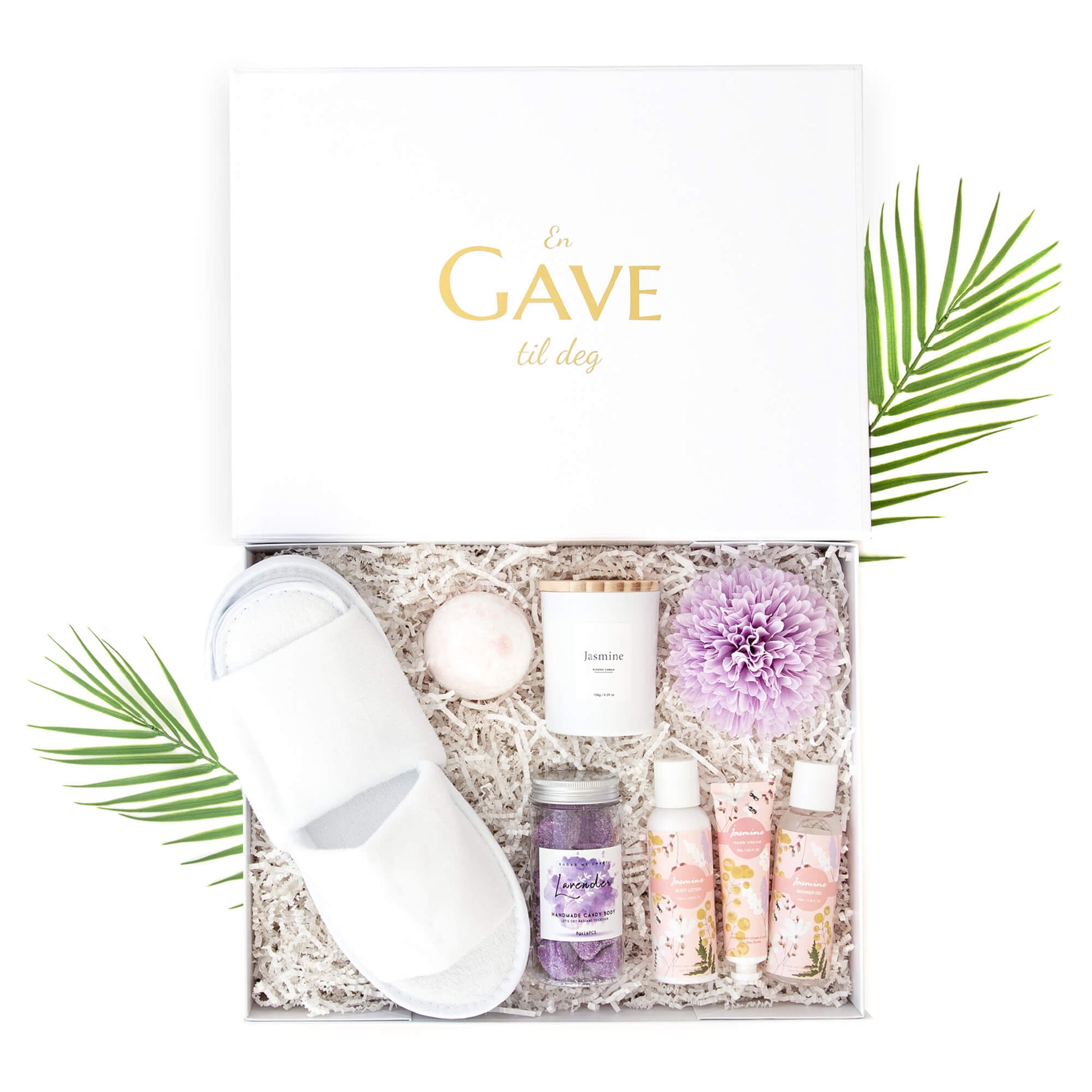 Velvære gave til henne med tøffler, badebombe, duftlys, badesett og bodyscrub, alt pakket i en fin gaveeske.