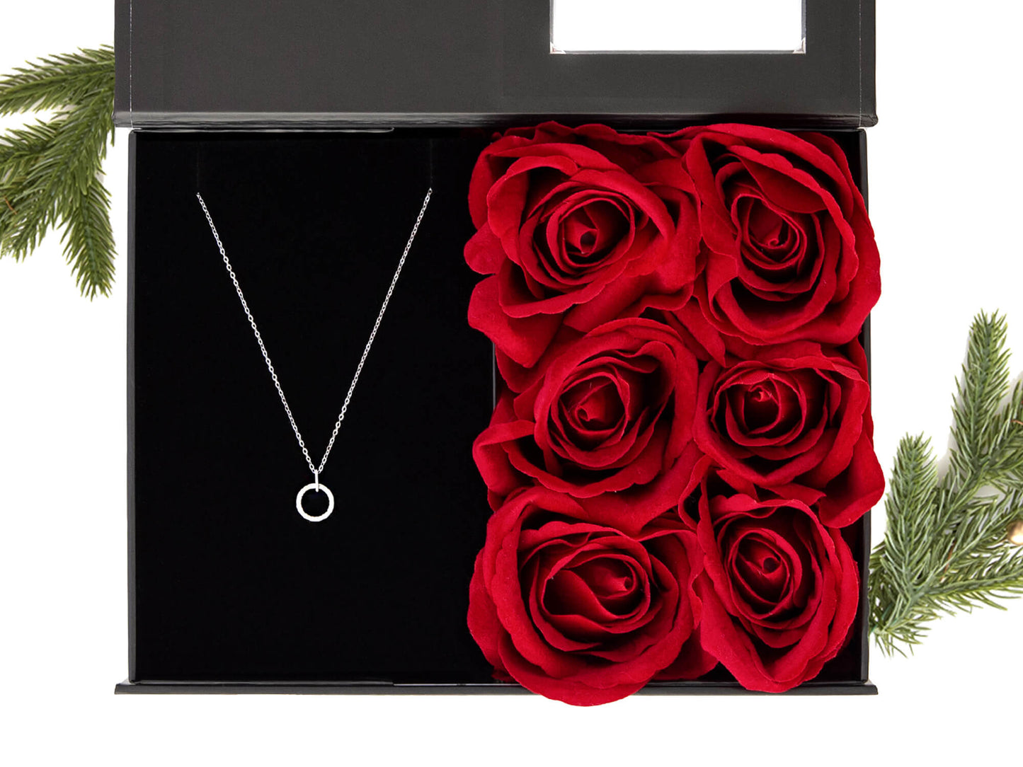 Svart gaveeske med vakre røde roser og et elegant smykke i sølv. Dekorert med juledekor
