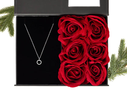 Svart gaveeske med vakre røde roser og et elegant smykke i sølv. Dekorert med juledekor
