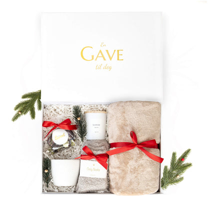 Julegave til henne med mykt pledd, sokker, duftlys, kopp og deilige sjokolader. Alt i en elegant åpen hvit gaveeske.