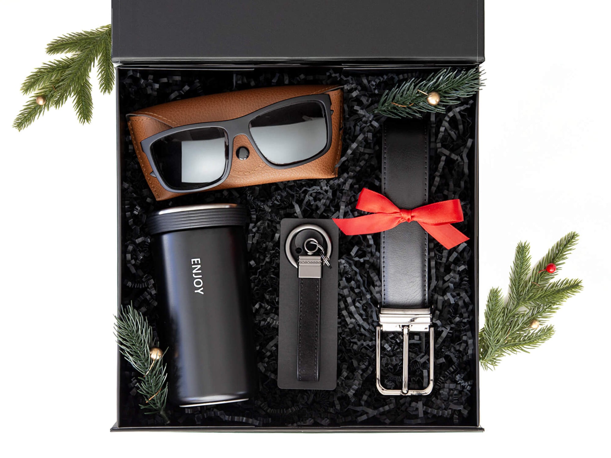 Svart gaveeske med nøkkelring, termokopp, solbriller og belte. Dekorert med juledekor