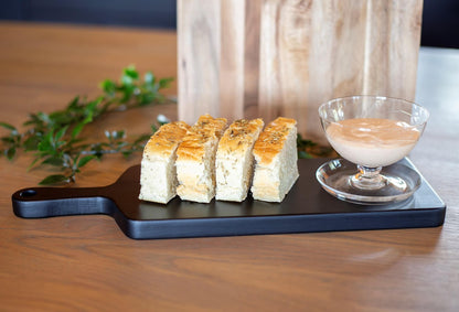 Sort serveringsbrett med focaccia i skiver og aioli i en glasskål