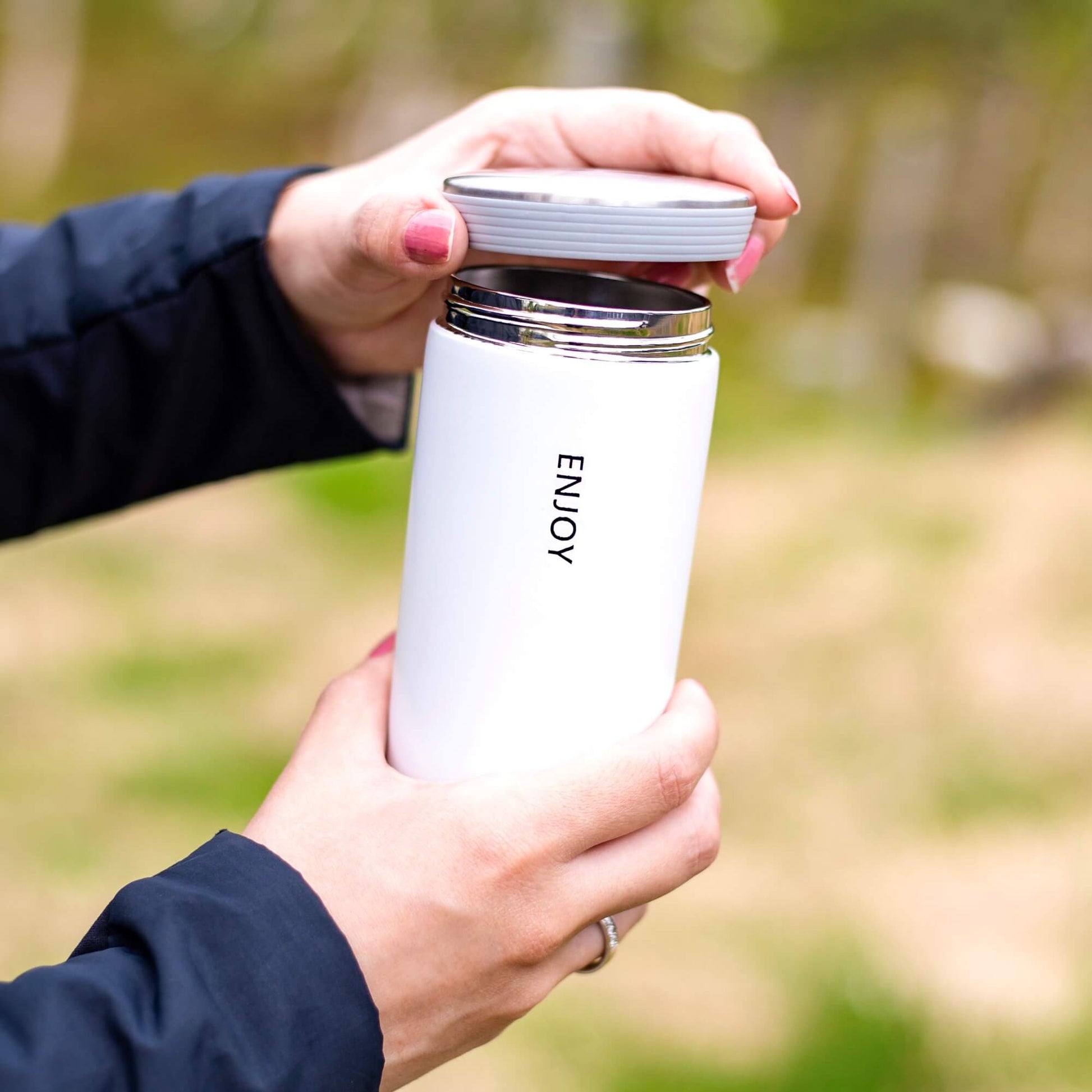Hvit termokopp med teksten ENJOY og avtakbart lokk