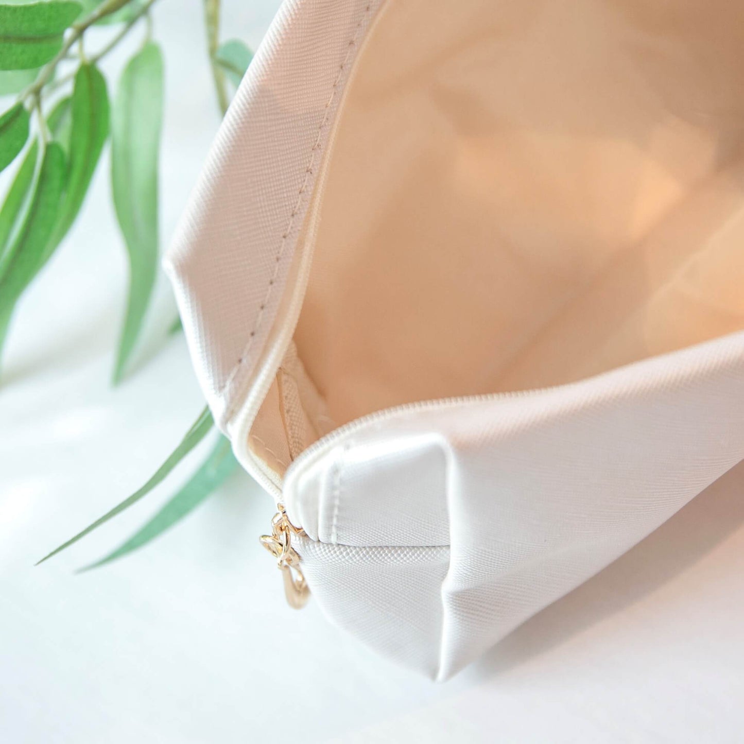 Åpen beige toalettmappe med lyst innvendig rom og glidelås